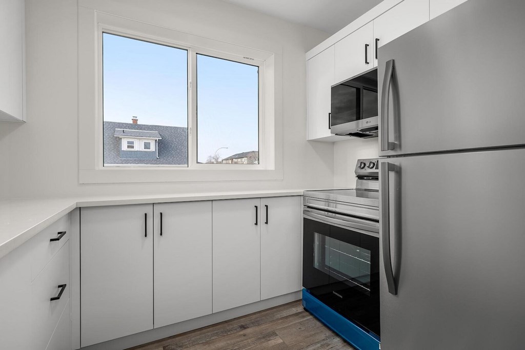 A kitchen with white cabinets and a black fridge.