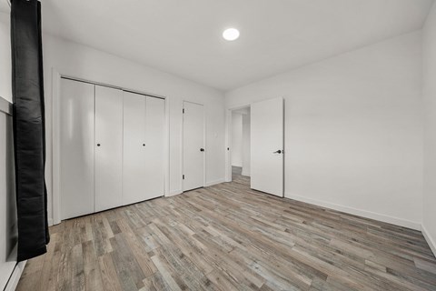 A room with white walls and wooden flooring with a black curtain on the left side.