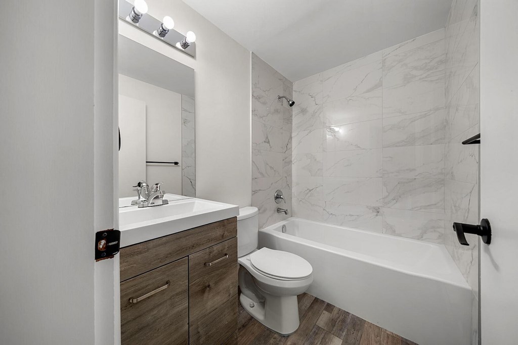 A white bathroom with a marble wall and a white tub.