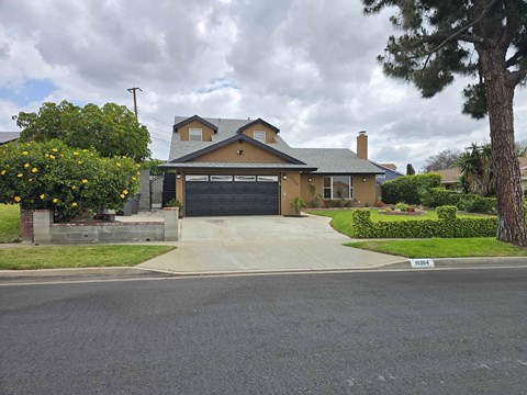 A house with a grey garage door and a driveway in front.