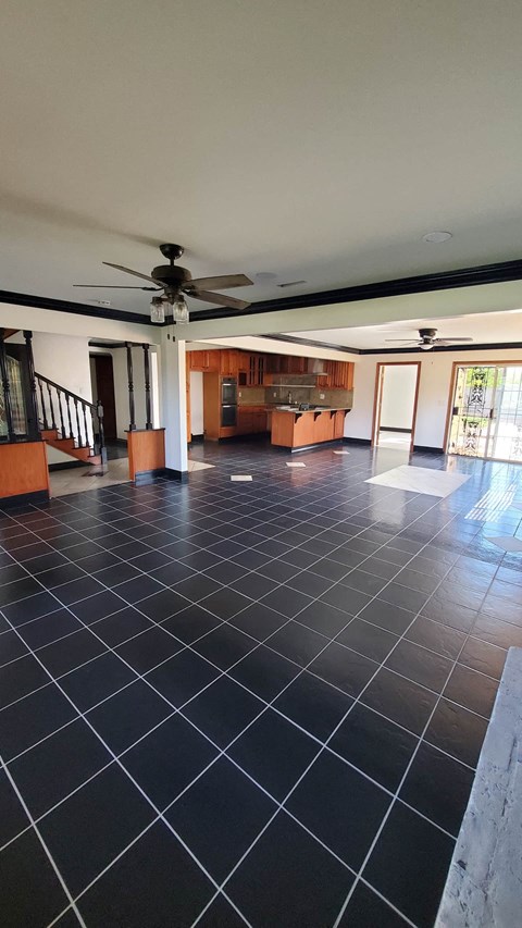A spacious room with a black tile floor and a ceiling fan.
