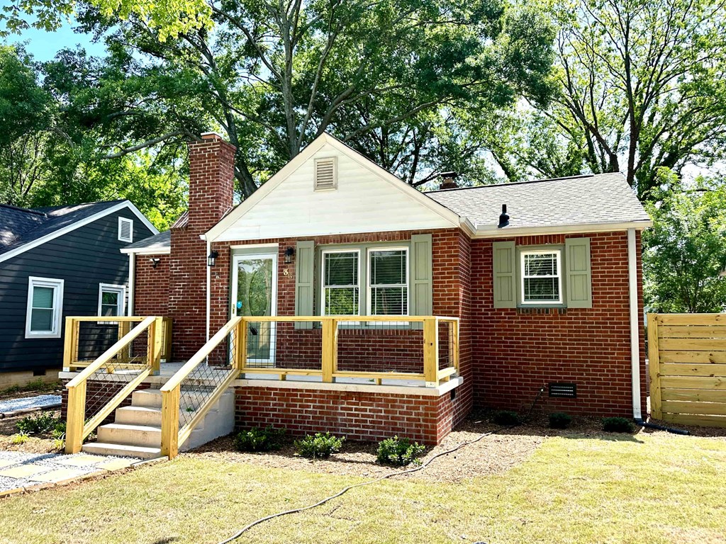A small brick house with a white roof and a wooden deck.