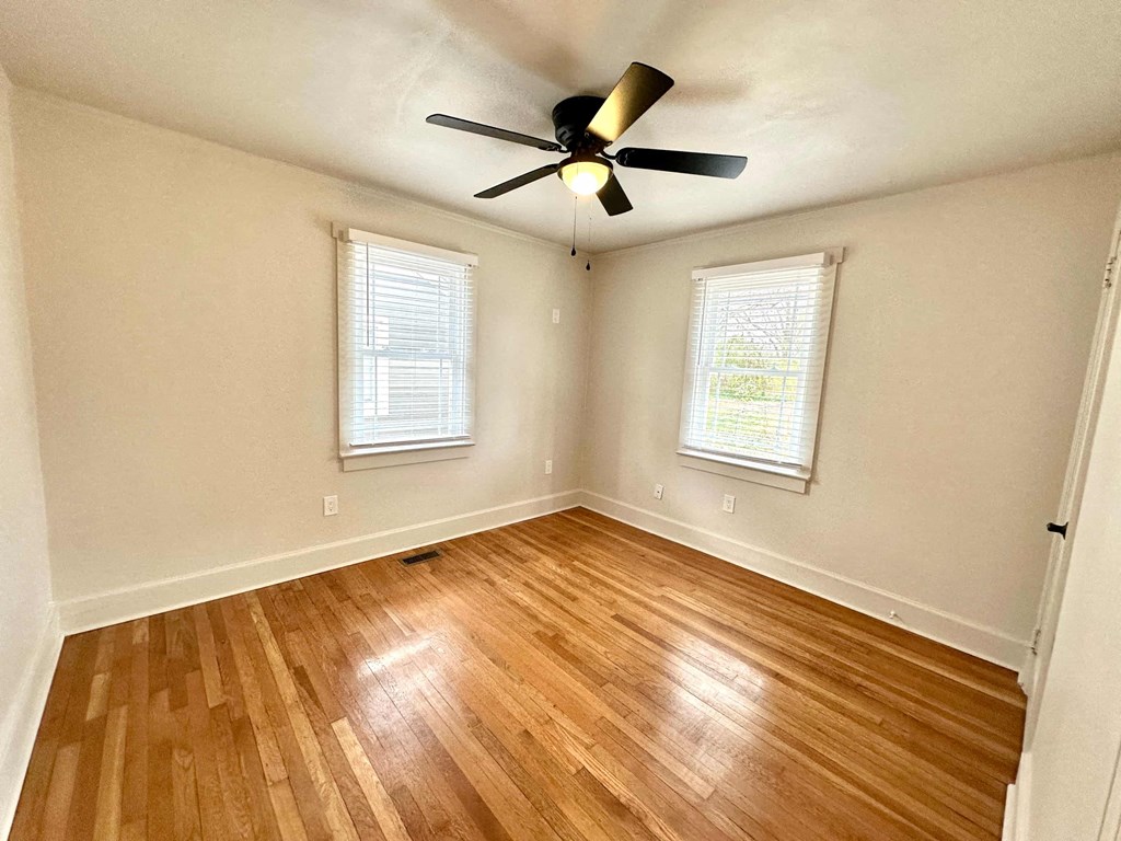 A room with wooden flooring and a ceiling fan.