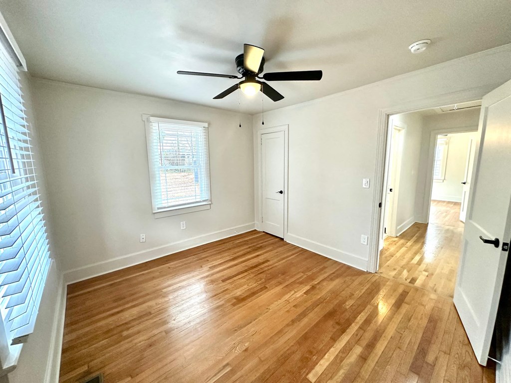 A room with a ceiling fan and wooden flooring.