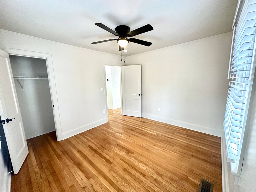 A room with a ceiling fan and wooden flooring.
