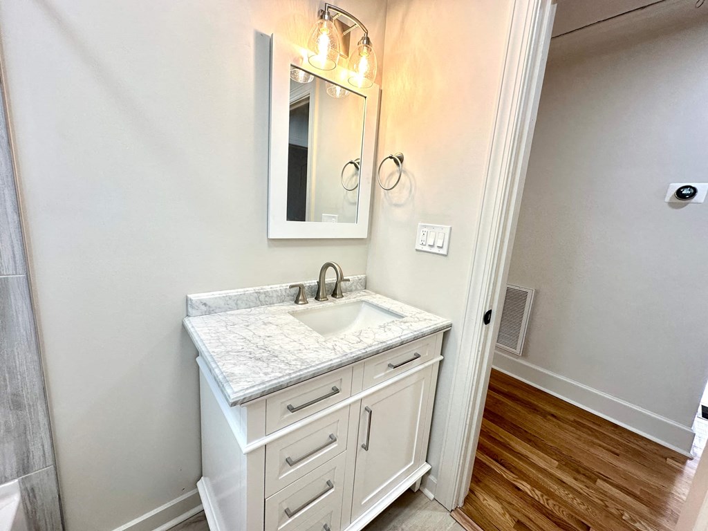 A bathroom with a marble countertop and a mirror above it.