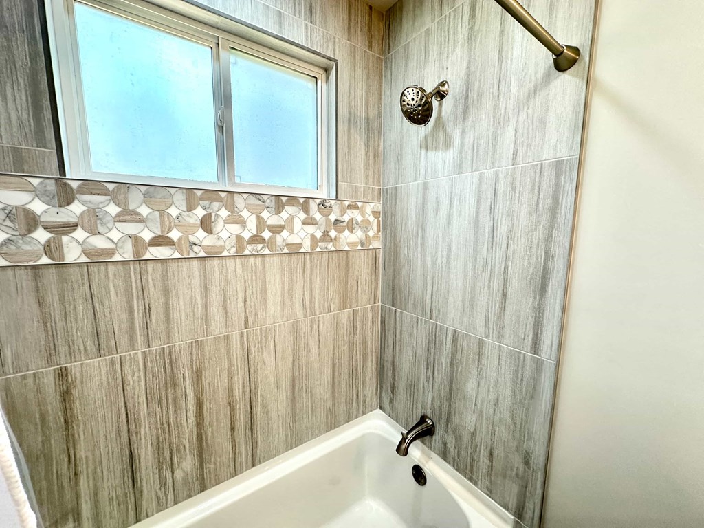 A bathroom with a tub, shower, and a window.