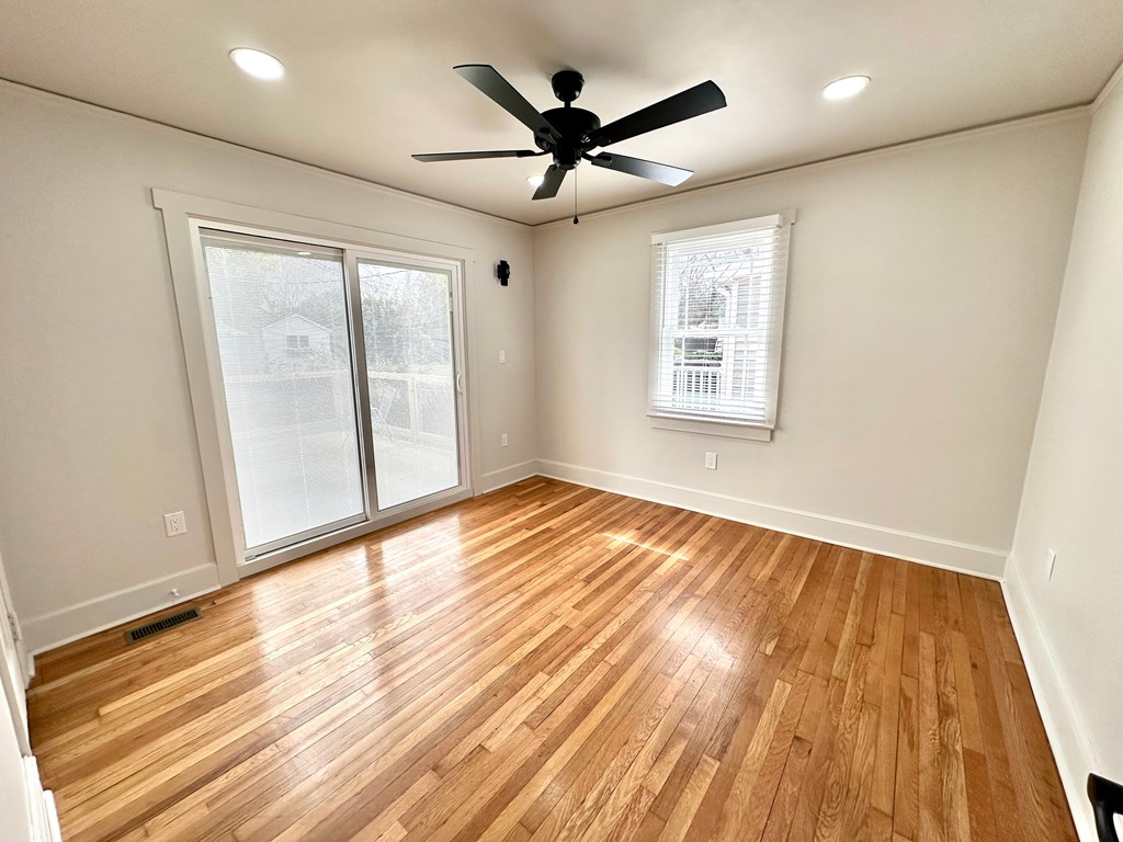 A room with a ceiling fan and wooden flooring.