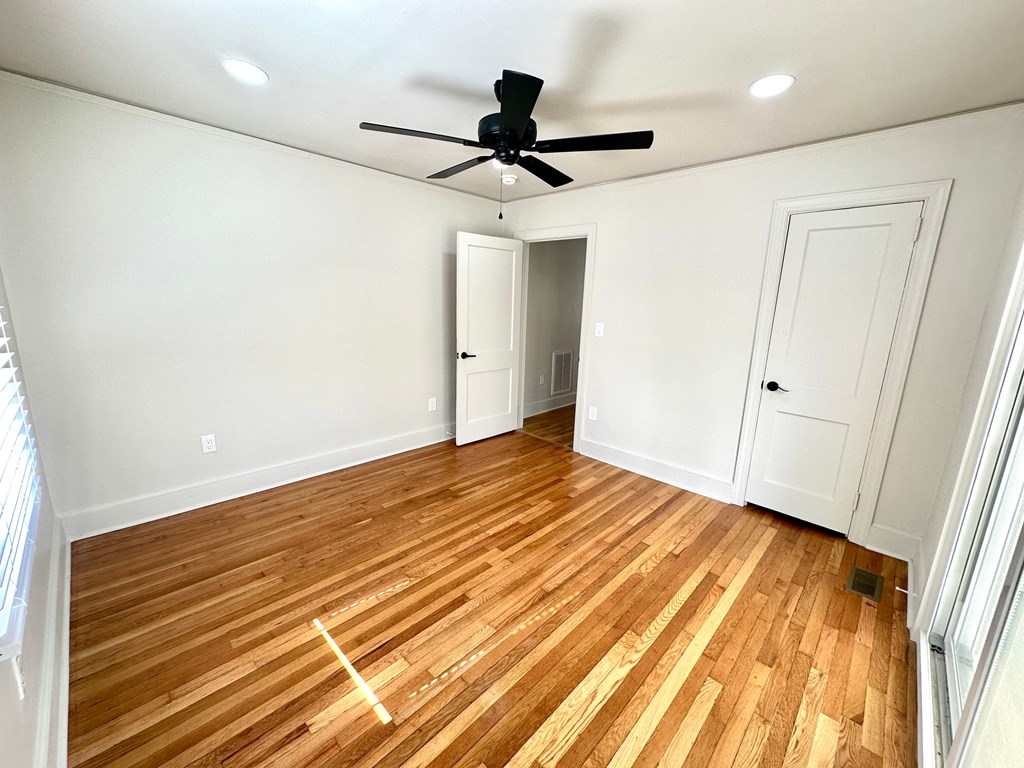 A room with a ceiling fan and wooden flooring.