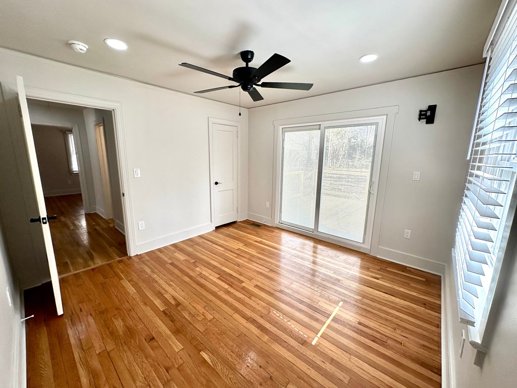 A room with a ceiling fan and wooden flooring.