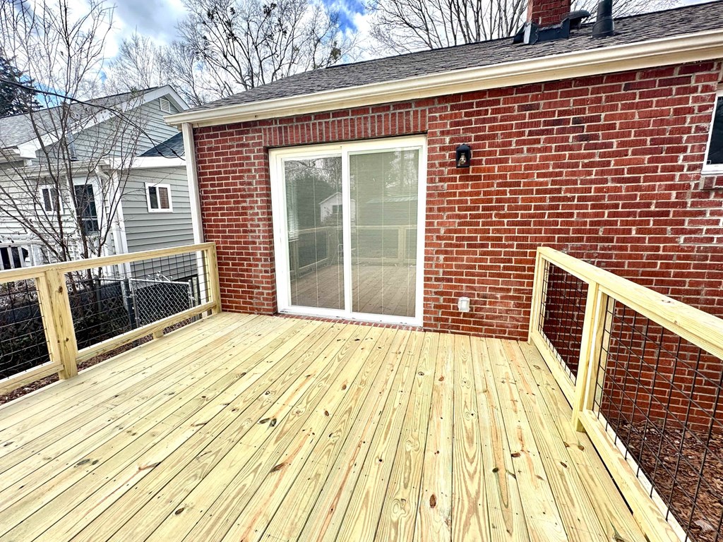A wooden deck with a glass door and a brick wall.