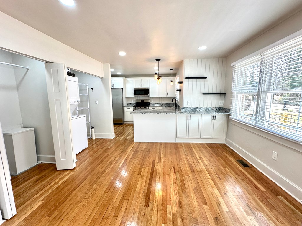 A kitchen with white cabinets and a wooden floor.