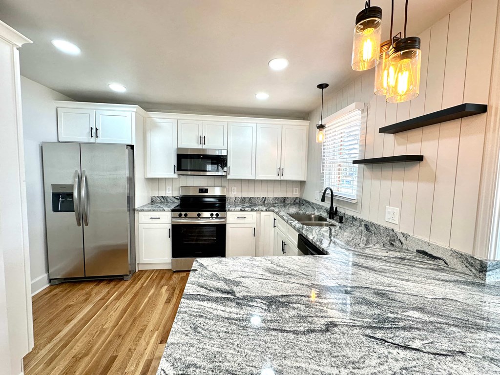 A kitchen with a marble countertop and wooden flooring.