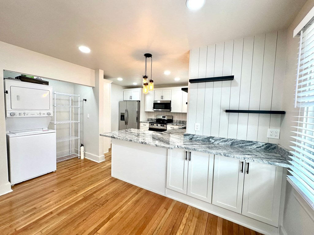 A kitchen with white cabinets and a marble countertop.