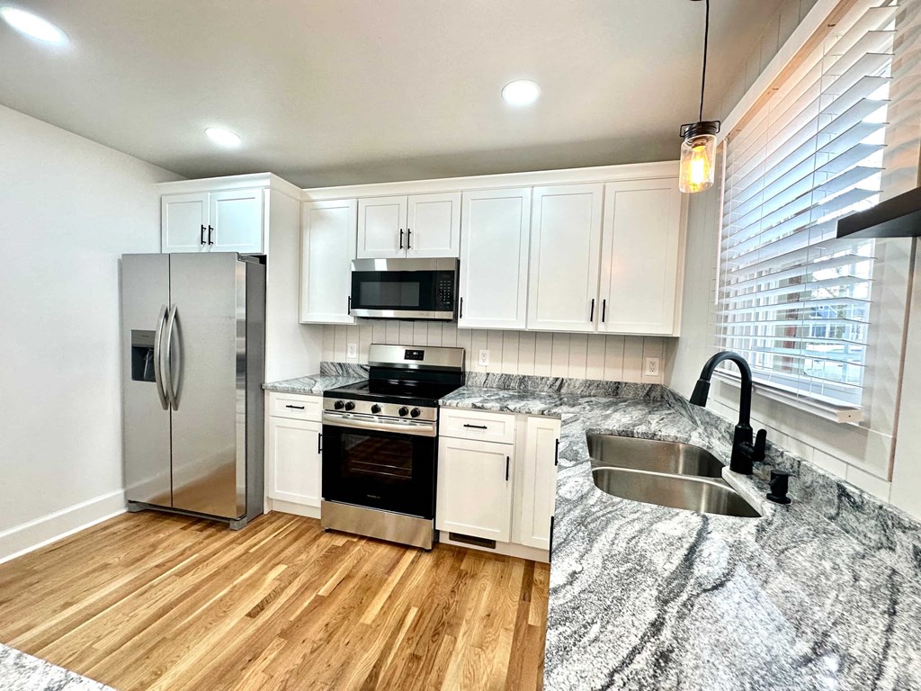 A kitchen with a stainless steel refrigerator, microwave, oven, and sink.