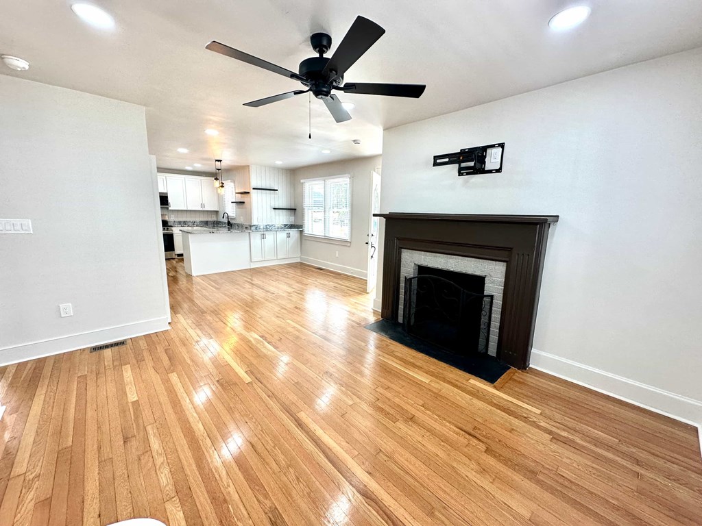 A living room with a fireplace and a ceiling fan.