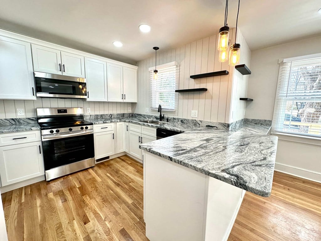 A kitchen with a marble countertop and wooden floors.