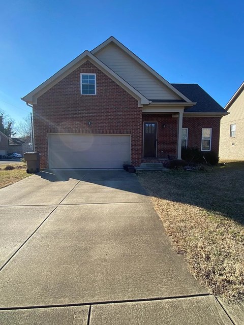 A red brick house with a white garage door and a driveway.