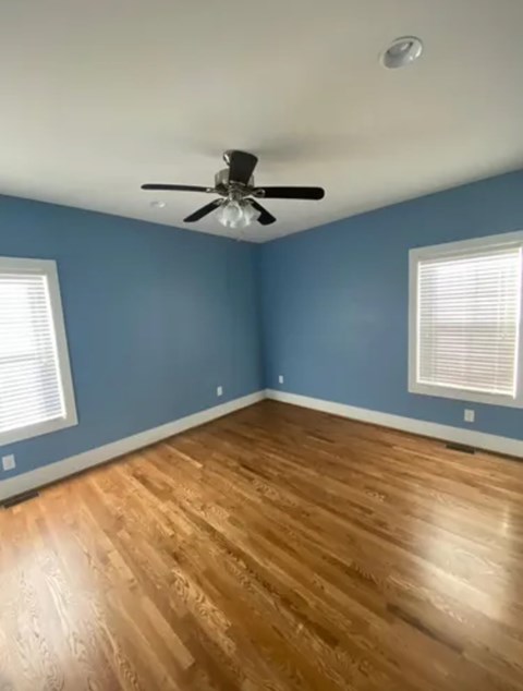 A room with a ceiling fan and wooden flooring.