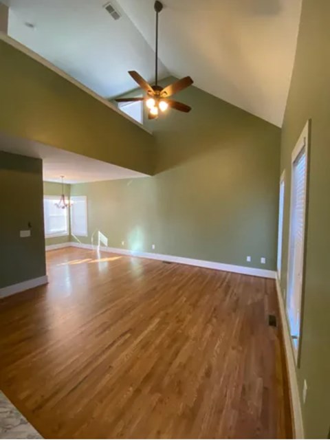 A room with a ceiling fan and wooden floors.