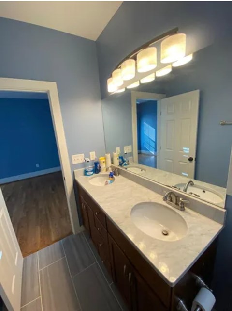 A bathroom with a sink, mirror, and lighting fixture.