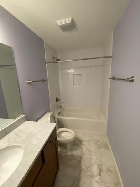 A white toilet is in a bathroom with a white tub and sink.