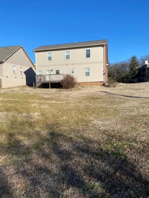 A large, two-story building with a balcony is situated in a grassy area with a smaller building to its left.