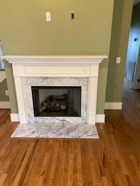 A fireplace with a white mantle and a fire burning inside.