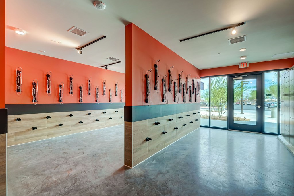 A gym with orange walls and a row of exercise equipment.