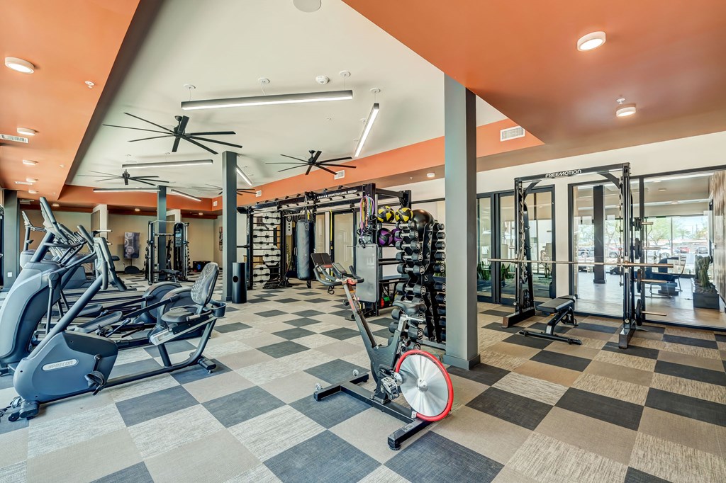 A gym with a variety of equipment including treadmills, weights, and exercise machines.