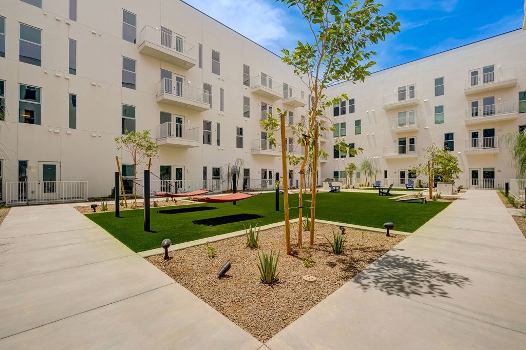A courtyard with a tree and a bench in front of a white building.