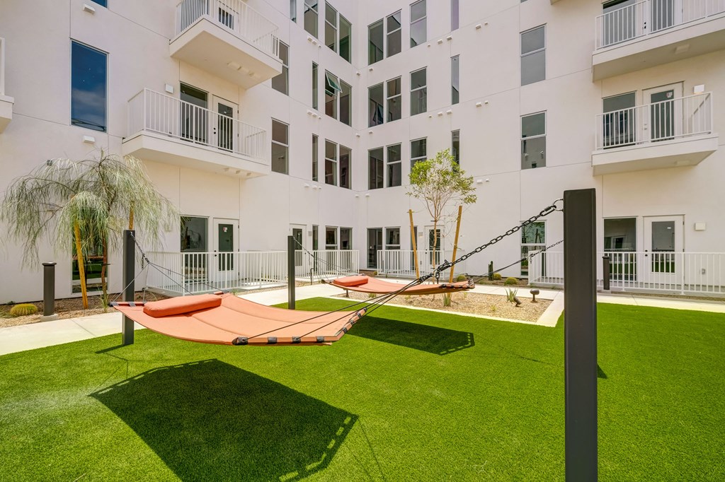 A white apartment building with a green lawn and orange trampoline.