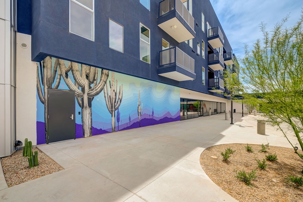 A building with a mural of a desert scene on its side.