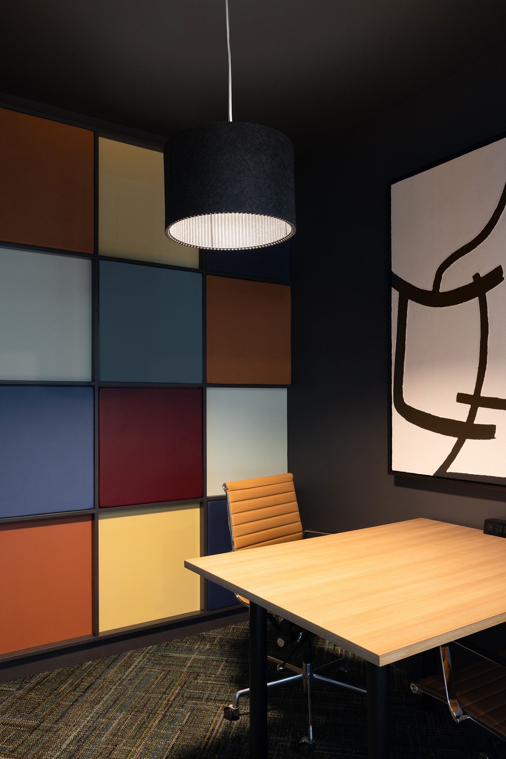 A modern office with a wooden table and a single orange chair.