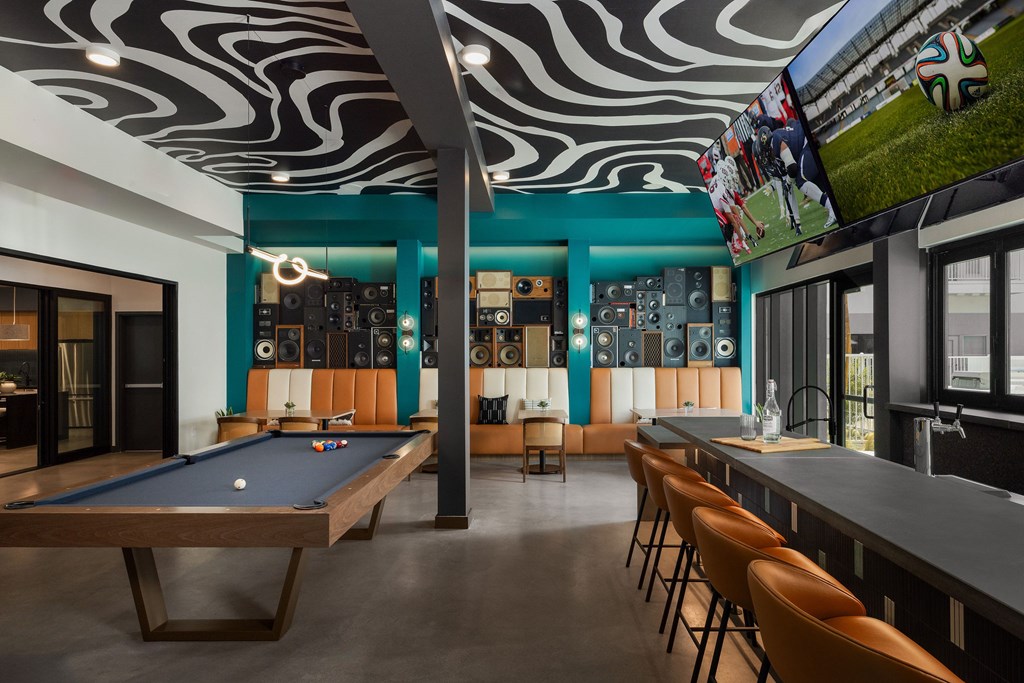 A room with a pool table and a bar area.