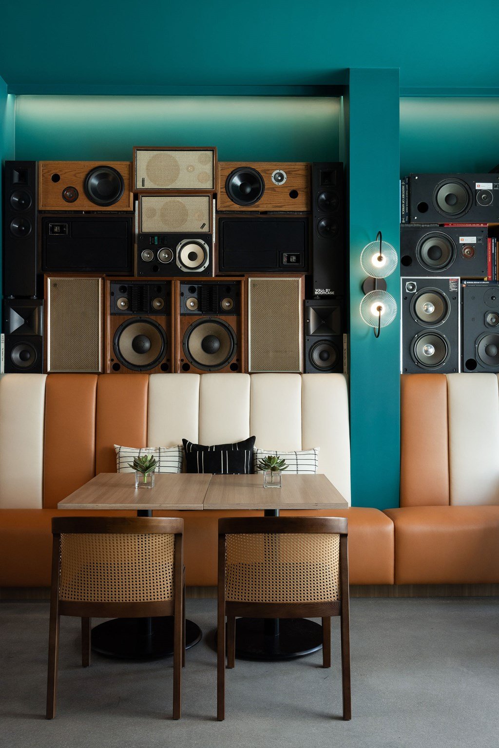 A room with a table and chairs and a wall of speakers.