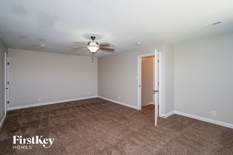 A room with a carpeted floor and a ceiling fan.