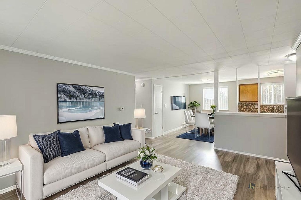 A living room with a white couch and a painting on the wall.