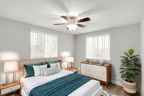 A bedroom with a bed, nightstands, and a ceiling fan.