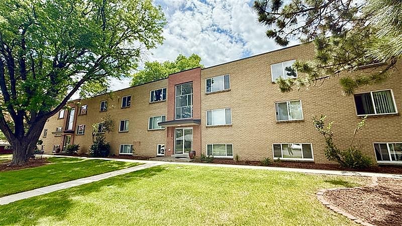 A large tree is in front of a brick apartment building.