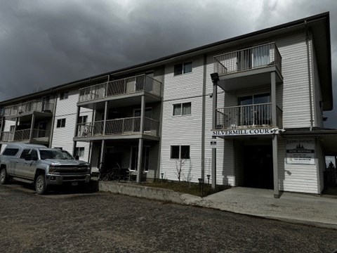 A silver SUV is parked in front of a building named Silvermill Court.