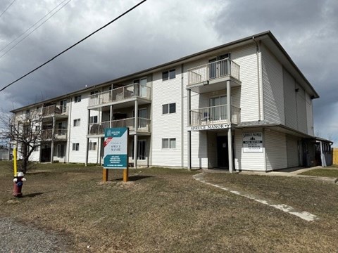 A large white apartment building with a sign in front that says "Public Housing".