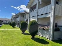 A row of houses with green lawns and bushes.