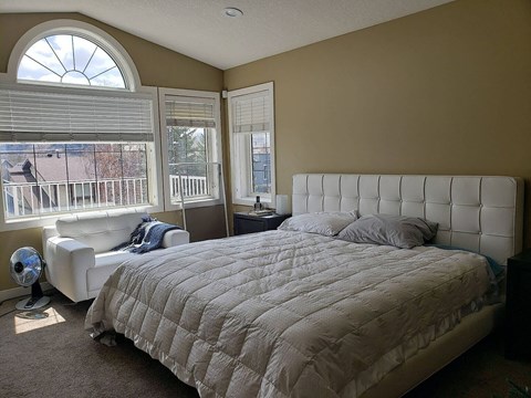 A bedroom with a large bed and a window with blinds.