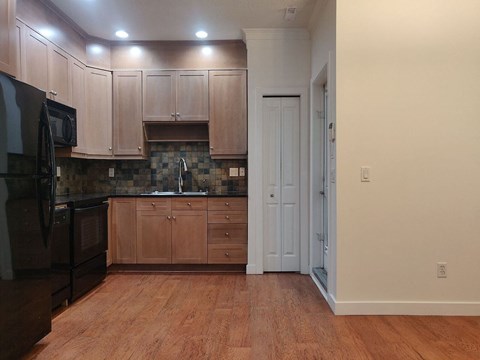 A kitchen with wooden cabinets and a black microwave.