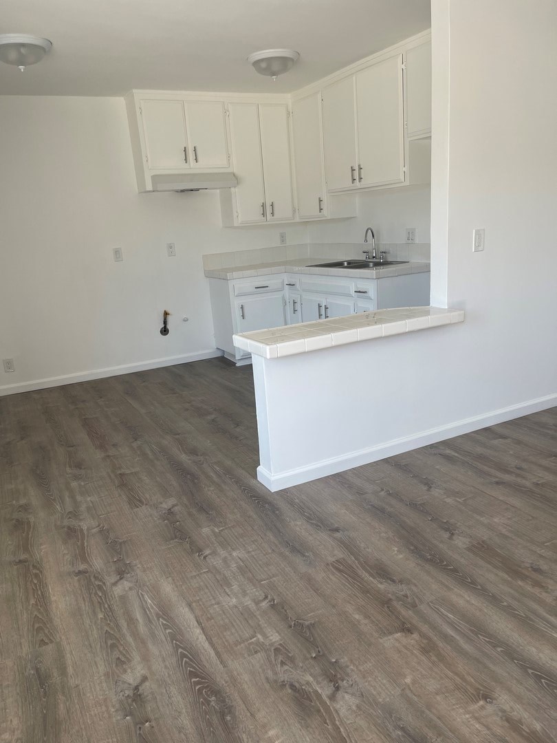 A kitchen with white cabinets and a wooden floor.