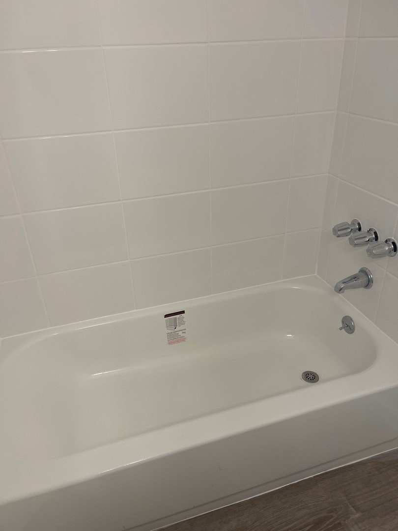 A white bathtub with a shower head and a faucet.