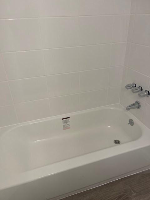 A white bathtub with a shower head and a faucet.