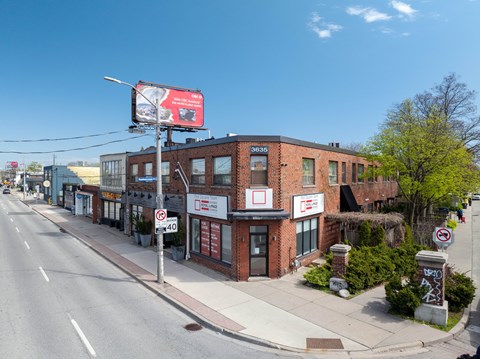 A street view with a building on the right and a billboard on the left.