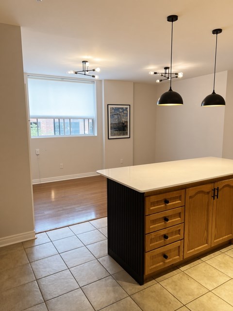 A kitchen with a white counter top and wooden cabinets.